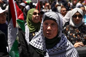 An elderly Palestinian woman lifts a national flag during a rally marking Nakba day in the Ramallah city centre in the occupied West Bank last year.