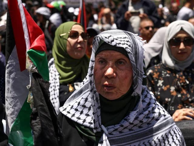 An elderly Palestinian woman lifts a national flag during a rally marking Nakba day in the Ramallah city centre in the occupied West Bank last year.