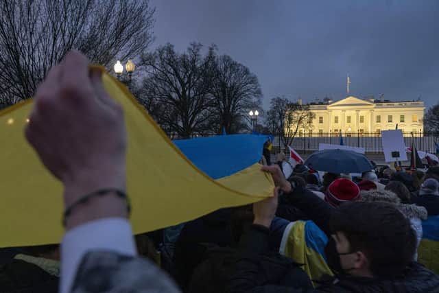 People hold a giant Ukrainian flag during a vigil to protest the Russian invasion of Ukraine in front of the White House in Washington, Thursday, Feb. 24, 2022. (AP Photo/Andrew Harnik)