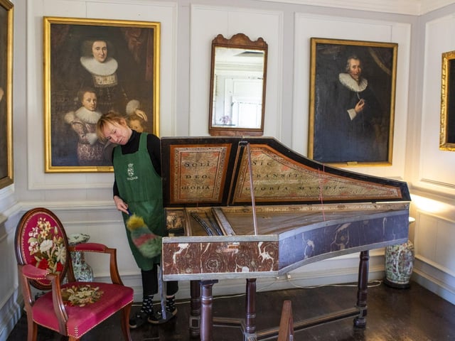 Housekeeper Lucy Whiteman dusts a harpsicord in the High Drawing Room.