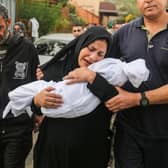 A woman cradles her son, eight-month-old Muhammad Bilal Abu Salah, as residents collect the bodies of Palestinians killed in reported Israeli air strikes.