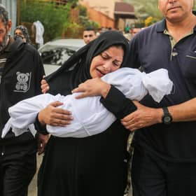 A woman cradles her son, eight-month-old Muhammad Bilal Abu Salah, as residents collect the bodies of Palestinians killed in reported Israeli air strikes.