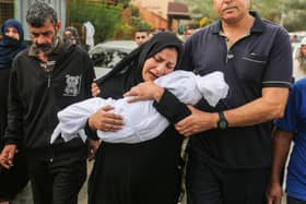 A woman cradles her son, eight-month-old Muhammad Bilal Abu Salah, as residents collect the bodies of Palestinians killed in reported Israeli air strikes.