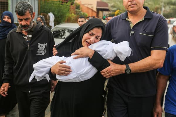 A woman cradles her son, eight-month-old Muhammad Bilal Abu Salah, as residents collect the bodies of Palestinians killed in reported Israeli air strikes.