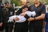 A woman cradles her son, eight-month-old Muhammad Bilal Abu Salah, as residents collect the bodies of Palestinians killed in reported Israeli air strikes.