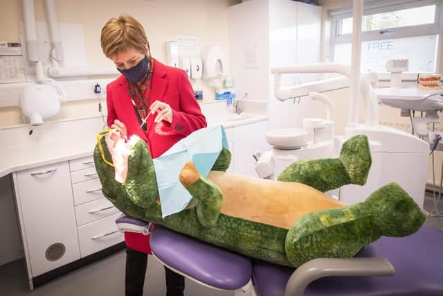 Nicola Sturgeon checks the teeth of "Dentosaurus" during a visit to the Thornliebank Dental Care centre in Glasgow.