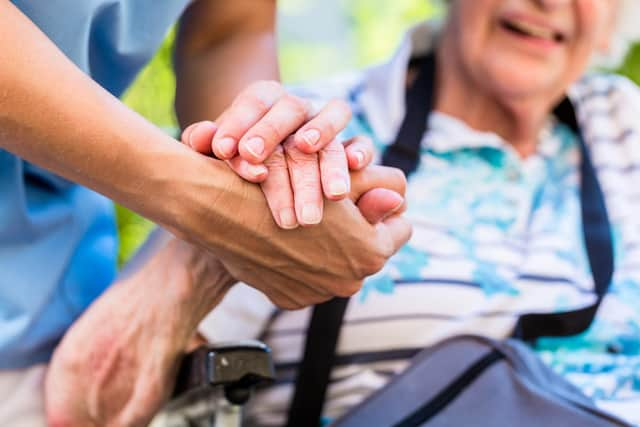 A nurse holds the hand of an older woman