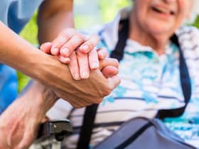 A nurse holds the hand of an older woman