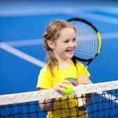 Child playing tennis on indoor court.