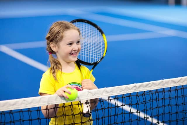 Child playing tennis on indoor court.