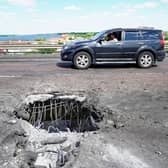 A picture taken on July 21, 2022 shows a car moving past a crater on Kherson's Antonovsky (Antonivskiy) bridge across the Dnipro river caused by a Ukrainian rocket strike, amid the ongoing Russian military action in Ukraine. (Photo by STRINGER / AFP) (Photo by STRINGER/AFP via Getty Images)