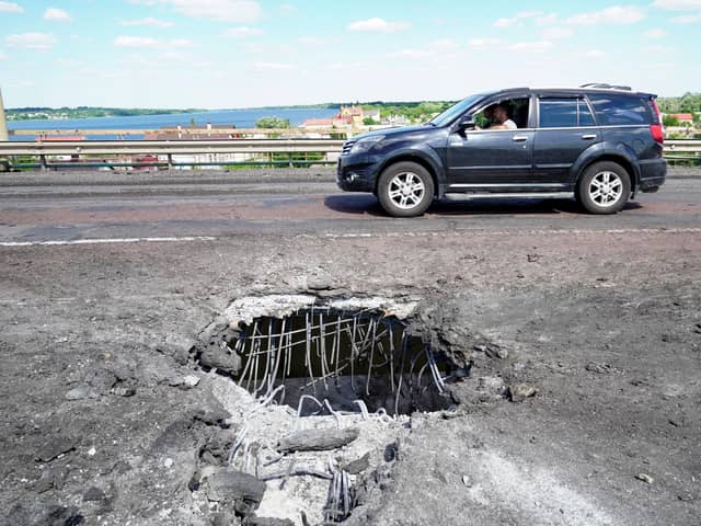 A picture taken on July 21, 2022 shows a car moving past a crater on Kherson's Antonovsky (Antonivskiy) bridge across the Dnipro river caused by a Ukrainian rocket strike, amid the ongoing Russian military action in Ukraine. (Photo by STRINGER / AFP) (Photo by STRINGER/AFP via Getty Images)