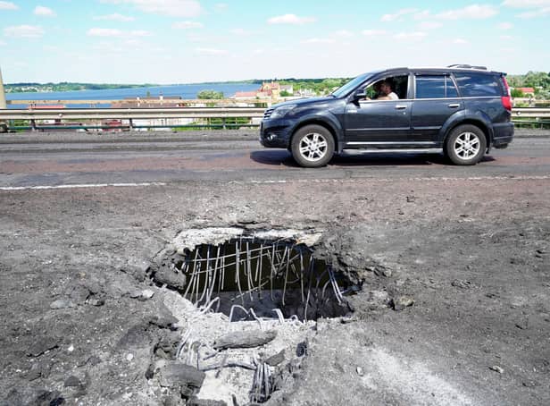 A picture taken on July 21, 2022 shows a car moving past a crater on Kherson's Antonovsky (Antonivskiy) bridge across the Dnipro river caused by a Ukrainian rocket strike, amid the ongoing Russian military action in Ukraine. (Photo by STRINGER / AFP) (Photo by STRINGER/AFP via Getty Images)