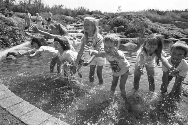 Children from Crookfur primary school cool off in the waterfall when temperatures hit 75 F (23 °C) at Glasgow Garden Festival, June 1988.