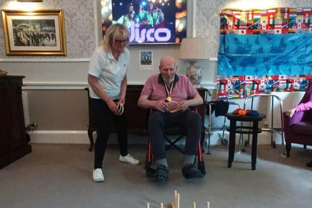Margaret Finch, Wellbeing Coordinator at HC-One Scotland’s Murrayfield House Care Home assisting resident Hector with taking part with the home’s Olympic Games