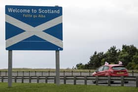 A car adorned with St George's Cross flags passes a welcome sign as it crosses the border into Scotland near Berwick-upon-Tweed. Picture: AFP via Getty Images