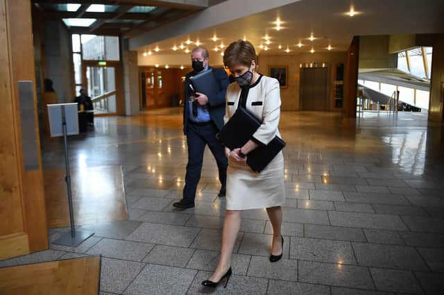 First Minister Nicola Sturgeon, wearing a face mask, walks to the chamber ahead of a statement on new COVID-19 restrictions at the Scottish Parliament in Holyrood, Edinburgh.