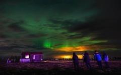 People watch the Northern Lights on a farm in Arabaer near Selfoss in Iceland.