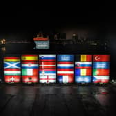 Stacked containers in the arrangement of the final draw stand at a terminal in the port of Hamburg at Elbphilharmonie, with the saltire shining bright.