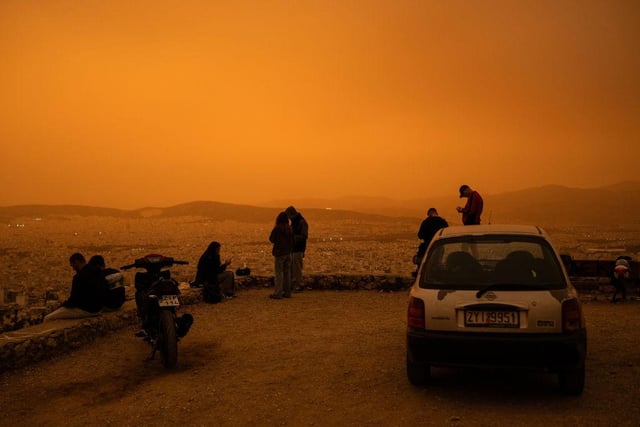 Friends gather to watch the dust storm on a hill on the edge of Athens.
