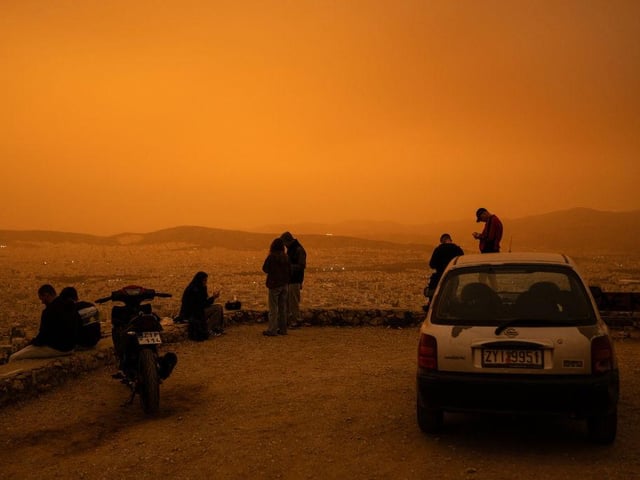 Friends gather to watch the dust storm on a hill on the edge of Athens.