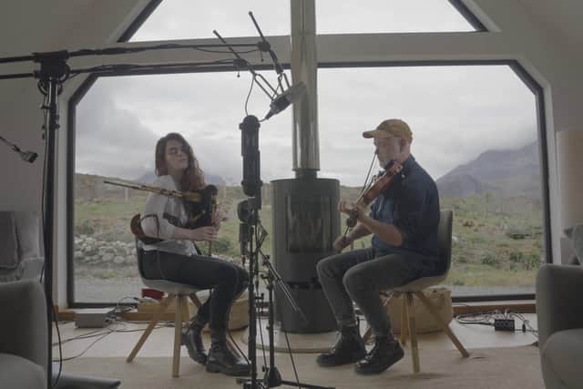 Brighde Chaimbeul and Aidan O'Rourke performings against the backdrop of the Black Cuillin mountains on Skye.
