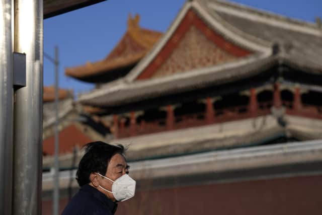 A resident wears a mask as he stands near the Lama Temple in Beijing. . Companies welcomed China's decision to end quarantines for travellers from abroad as an important step to revive slumping business activity. (AP Photo/Ng Han Guan)