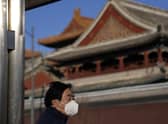 A resident wears a mask as he stands near the Lama Temple in Beijing. . Companies welcomed China's decision to end quarantines for travellers from abroad as an important step to revive slumping business activity. (AP Photo/Ng Han Guan)