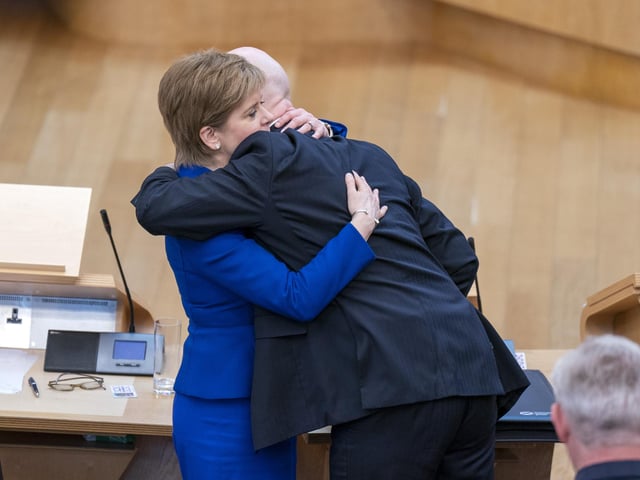 Outgoing First Minister Nicola Sturgeon and outgoing Deputy First Minister John Swinney hug before leaving the main chamber after her last First Minster's Questions (FMQs) in the main chamber of the Scottish Parliament in Edinburgh.