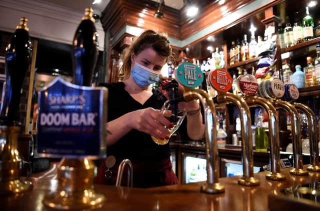 A server wearing a face mask or covering due to the Covid-19 pandemic pours a pint. Picture: Daniel Leal-Olivas/AFP via Getty Images