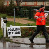 A Royal Mail postman walks past a polling station sign