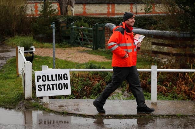 A Royal Mail postman walks past a polling station sign