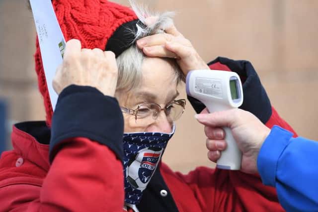 Fans have their temperature checked as a return of supporters to stadia is trialed during the Scottish Premiership match between Ross County and Celtic at the Global Energy Stadium, on September 12, 2020, in Dingwall, Scotland. (Photo by Craig Williamson / SNS Group)