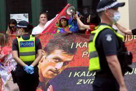 Protestors hold placards up at a government detention centre where Serbia's tennis champion Novak Djokovic is reported to be staying in Melbourne. (Photo by WILLIAM WEST/AFP via Getty Images)