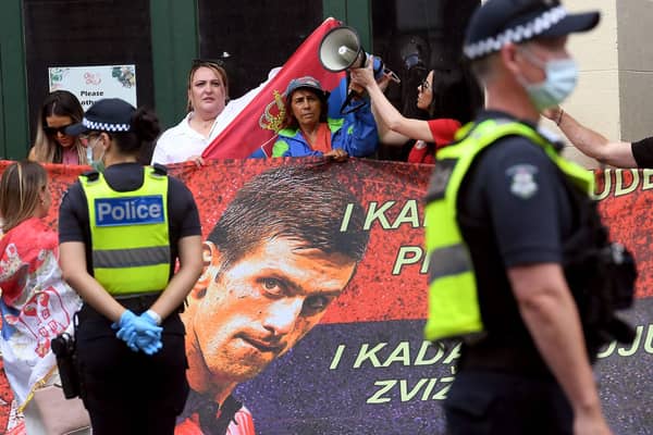Protestors hold placards up at a government detention centre where Serbia's tennis champion Novak Djokovic is reported to be staying in Melbourne. (Photo by WILLIAM WEST/AFP via Getty Images)