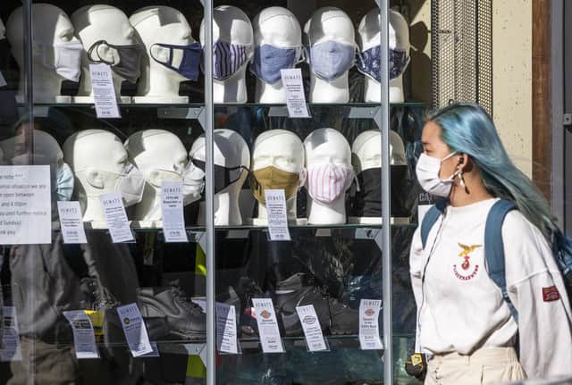 A woman wearing a protective face mask walks past a shop selling masks in Edinburgh city centre. Picture: Jane Barlow/PA Wire