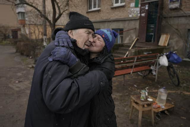 A woman kisses a man while cooking on an open fire outside an apartment building which had no electricity, water or gas since the beginning of the Russian invasion in Bucha, Ukraine, where widespread atrocities against civilians have been reported. (AP Photo/Vadim Ghirda)