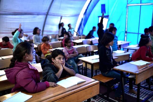Syrian children take lessons in a makeshift school tent in a refugee camp in Turkey in 2015.