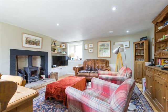 The spacious living-dining room benefits from an original stone fireplace and sold-fuel stove