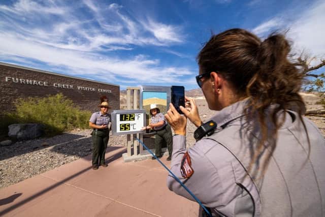 US park rangers photograph one another next to the unofficial thermometer at the Furnace Creek Visitor Center in Death Valley National Park, which indicates a temperature of 55 degrees, which would set a new world heat record. However, the thermometer is known for showing temperatures that are inaccurately higher than the official temperature.