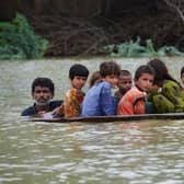 With a third of Pakistan said to be under water, a man and a youth use a satellite dish to move children across a flooded area  (Picture: Fida Hussain/AFP via Getty Images)