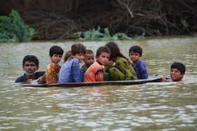 With a third of Pakistan said to be under water, a man and a youth use a satellite dish to move children across a flooded area  (Picture: Fida Hussain/AFP via Getty Images)