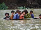 With a third of Pakistan said to be under water, a man and a youth use a satellite dish to move children across a flooded area  (Picture: Fida Hussain/AFP via Getty Images)