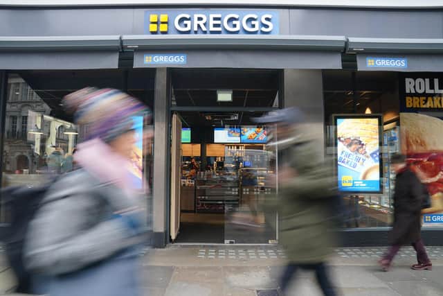Shoppers passing a new-look Greggs storefront.