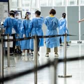 A man is directed to a waiting taxi at Hong Kong International Airport that will take him to hotel quarantine. Hong Kong announced on Friday it will end mandatory hotel quarantine from Monday.