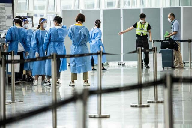 A man is directed to a waiting taxi at Hong Kong International Airport that will take him to hotel quarantine. Hong Kong announced on Friday it will end mandatory hotel quarantine from Monday.