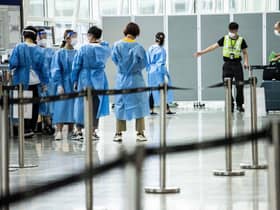 A man is directed to a waiting taxi at Hong Kong International Airport that will take him to hotel quarantine. Hong Kong announced on Friday it will end mandatory hotel quarantine from Monday.
