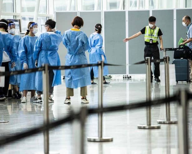 A man is directed to a waiting taxi at Hong Kong International Airport that will take him to hotel quarantine. Hong Kong announced on Friday it will end mandatory hotel quarantine from Monday.