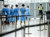 A man is directed to a waiting taxi at Hong Kong International Airport that will take him to hotel quarantine. Hong Kong announced on Friday it will end mandatory hotel quarantine from Monday.