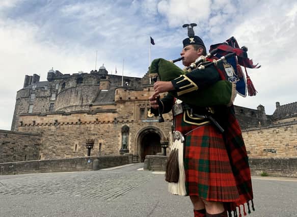 Pipe Major Stuart Gillies of 2 Scots plays the The Heroes of St Valery in front of Edinburgh Castle. The castle is among top  places British tourists plan to visit this year
